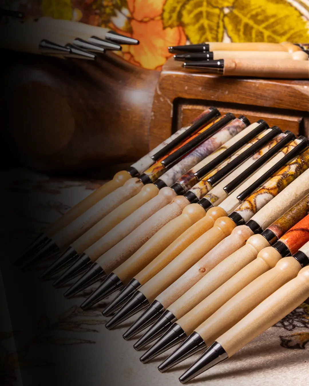 A row of custom handmade pens made as sympathy gifts from the fabric of a loved one's couch. The top half of the pens are colorful, being made from couch fabric. The bottom half are light wood.